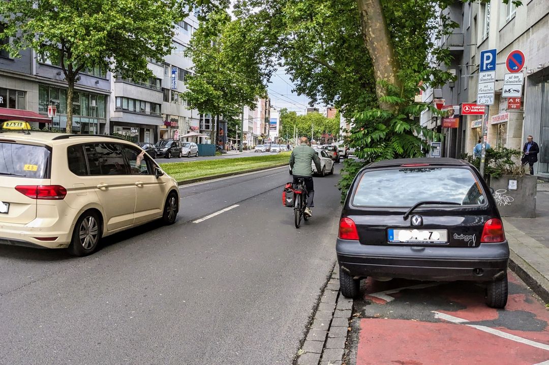 Gefährliches Fahrradfahren auf der Graf-Adolf-Straße. Kein Radweg schützt Radfahrende, die sich zwischen parkenden Autos und fließenden Verkehr ihren Weg suchen müssen. / Foto: ADFC Düsseldorf