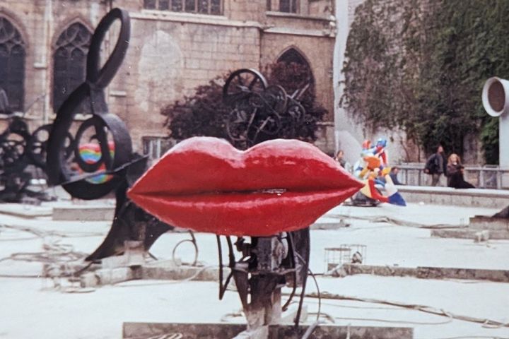 Niki de Saint Phalle, L'Amour, Fontaine Stravinsky, Paris 1991 Rotes Lippenpaar aus Kunstharz in einem trockenen Brunnenbecken, dahinter schwarze Metallskulpturen und eine gotische Kirche.