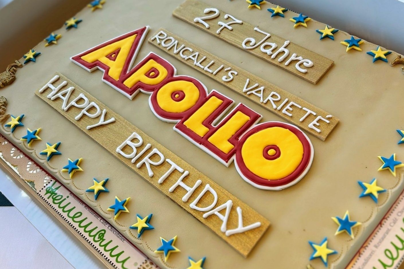 Die riesige Geburtstagstorte, die für den 27. Jahrestag von Roncalli's Apollo Varieté präsentiert wurde, erregte große Aufmerksamkeit. Die Torte war mit dem ikonischen Logo des Varietés verziert und mit bunten Sternen geschmückt. Vor 27 Jahren öffnete Roncalli's Apollo Varieté seine Pforten und wurde zum ersten speziell für Varietébetrieb errichteten Theater Deutschlands. Mit Unterstützung des damaligen Ministerpräsidenten Johannes Rau wurden Magie, Akrobatik und der Roncalli-Zauber nach Düsseldorf gebracht. / Foto (C) Roncalli Apollo Variété