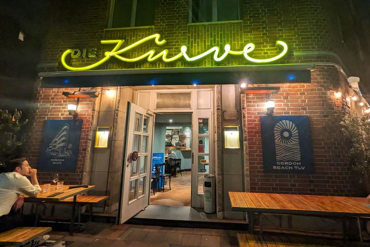 Die Kurve in Düsseldorf-Pempelfort bei Nacht Beleuchtete Backsteinfassade des Restaurants Die Kurve an der Goebenstraße in Düsseldorf-Pempelfort mit gelbem Neonschriftzug und geöffnetem Eingang.