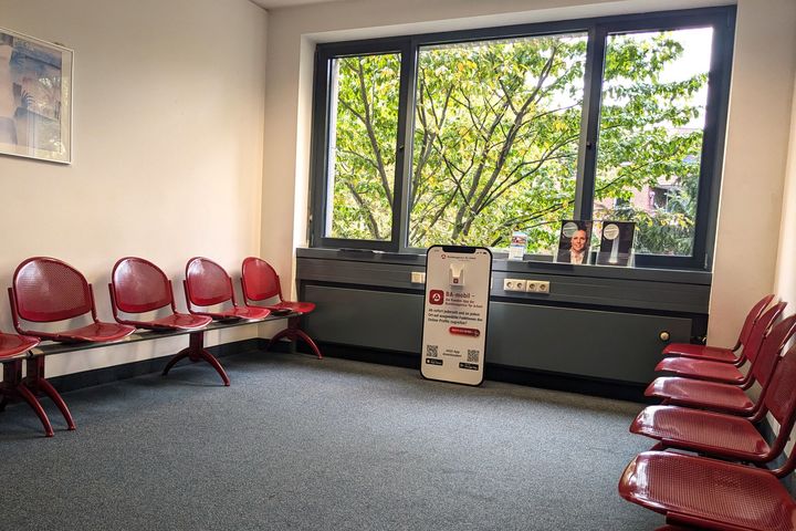 Berufsberatung in Düsseldorf Wartebereich der Agentur für Arbeit Düsseldorf mit roten Stühlen und Hinweisschild zur digitalen Beratung