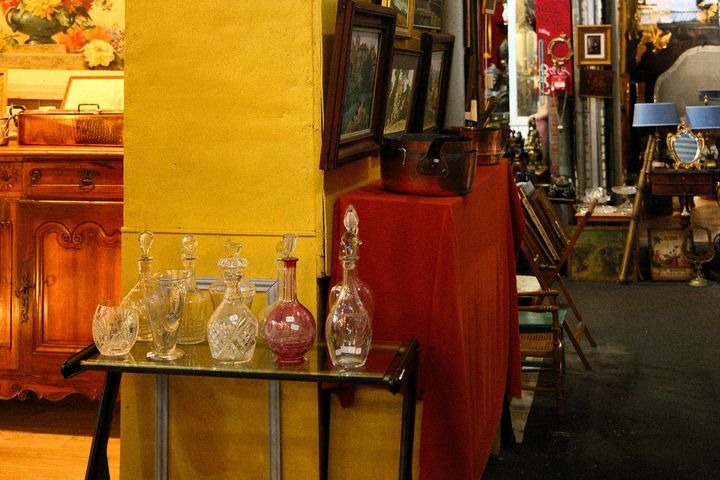 Antiquitäten und Fundstücke auf einem Flohmarkt Antiquitäten, Glasvasen, Bilderrahmen und Möbelstücke auf einem Flohmarktstand.