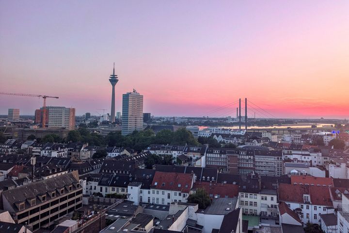Düsseldorf Stadtpanorama mit Wohnhäusern, Büroturm und Rhein bei Sonnenuntergang Blick über die Düsseldorfer Innenstadt bei Sonnenuntergang: dichte Wohnbebauung im Vordergrund, Rheinturm und Bürogebäude in der Mitte, Rheinkniebrücke und Rhein im Hintergrund, Baukran links im Bild.