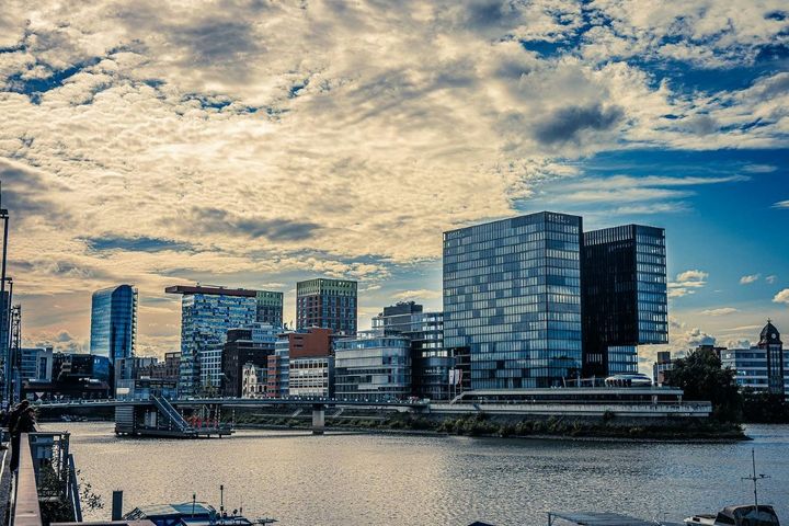 Düsseldorf zwischen Wirtschaft und Kapitalmarkt Blick über den Rhein auf moderne Büro- und Hotelgebäude im Düsseldorfer MedienHafen unter bewölktem Himmel.