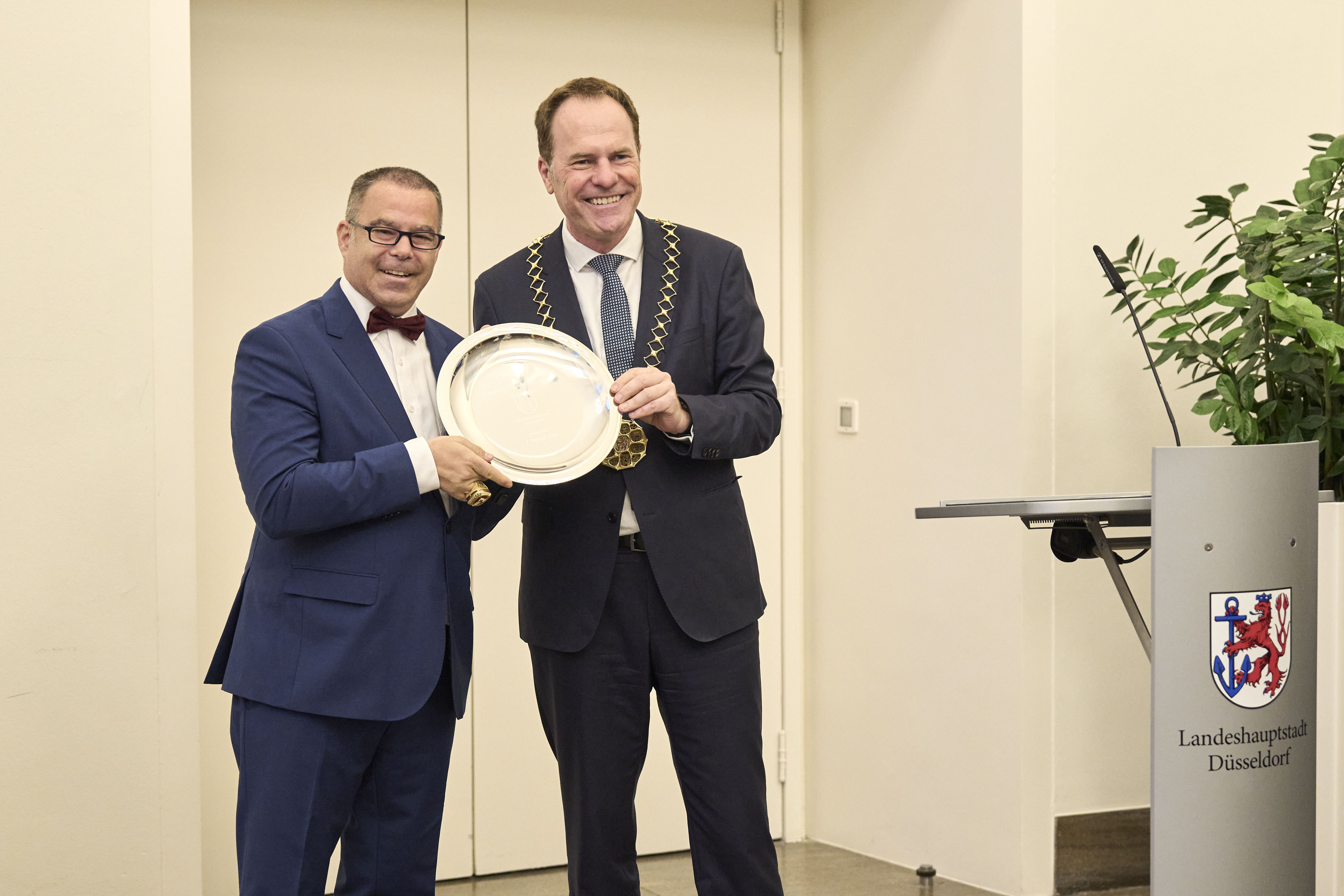 Oberbürgermeister Dr. Stephan Keller (r.) hat zur Erinnerung an den Titelgewinn einen gravierten Stahlteller an Daniel Thywissen, Geschäftsführender Gesellschafter von Rhein Fire, überreicht © Landeshauptstadt Düsseldorf/Claus Langer 