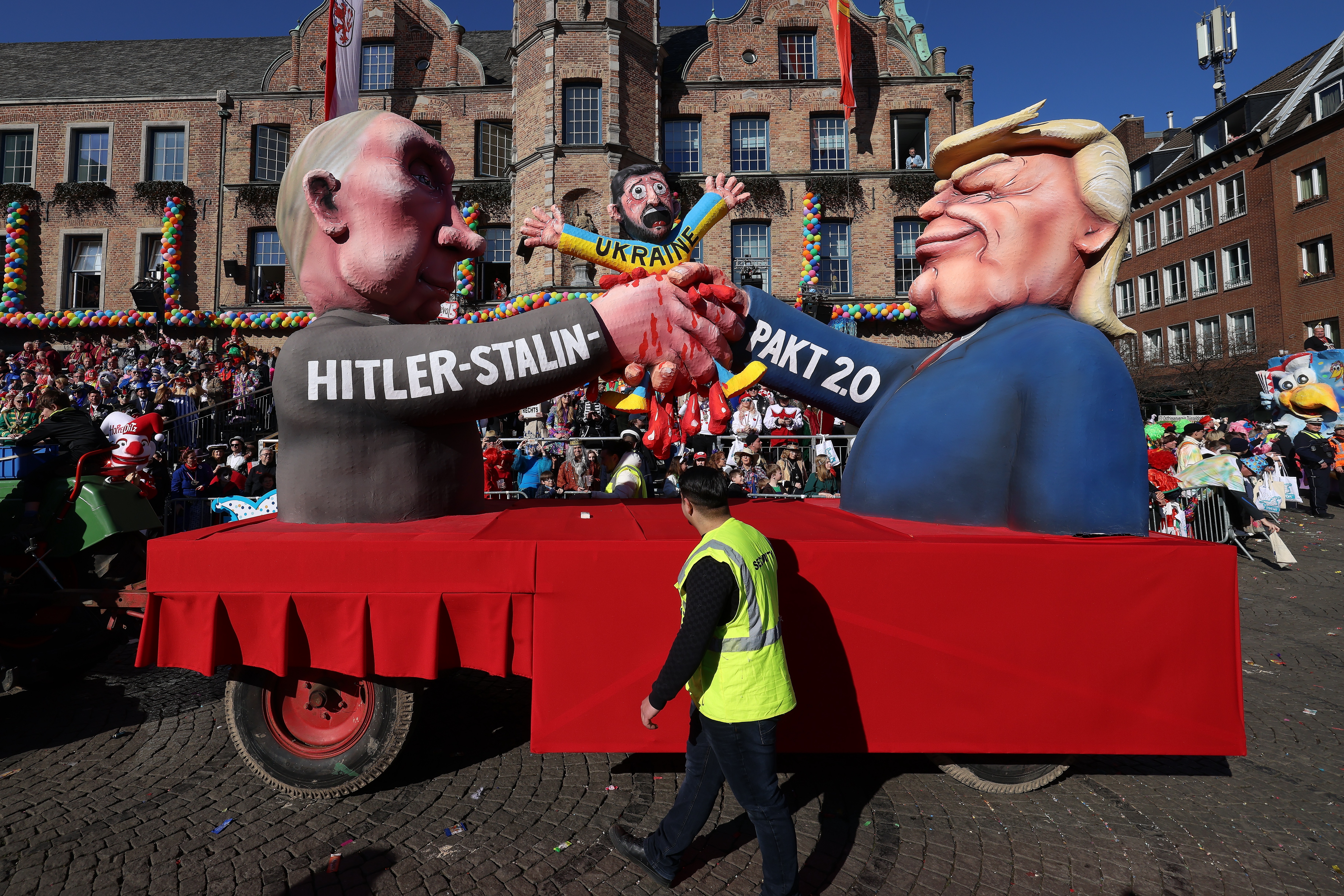 Mottowagen im Rosenmontagszug 2025: Der ukrainische Präsident Wolodymyr Selenskyj wird blutig zerquetscht von US–Präsident Donald Trump und dem russischen Präsidenten Wladimir Putin © Landeshauptstadt Düsseldorf/David Young 